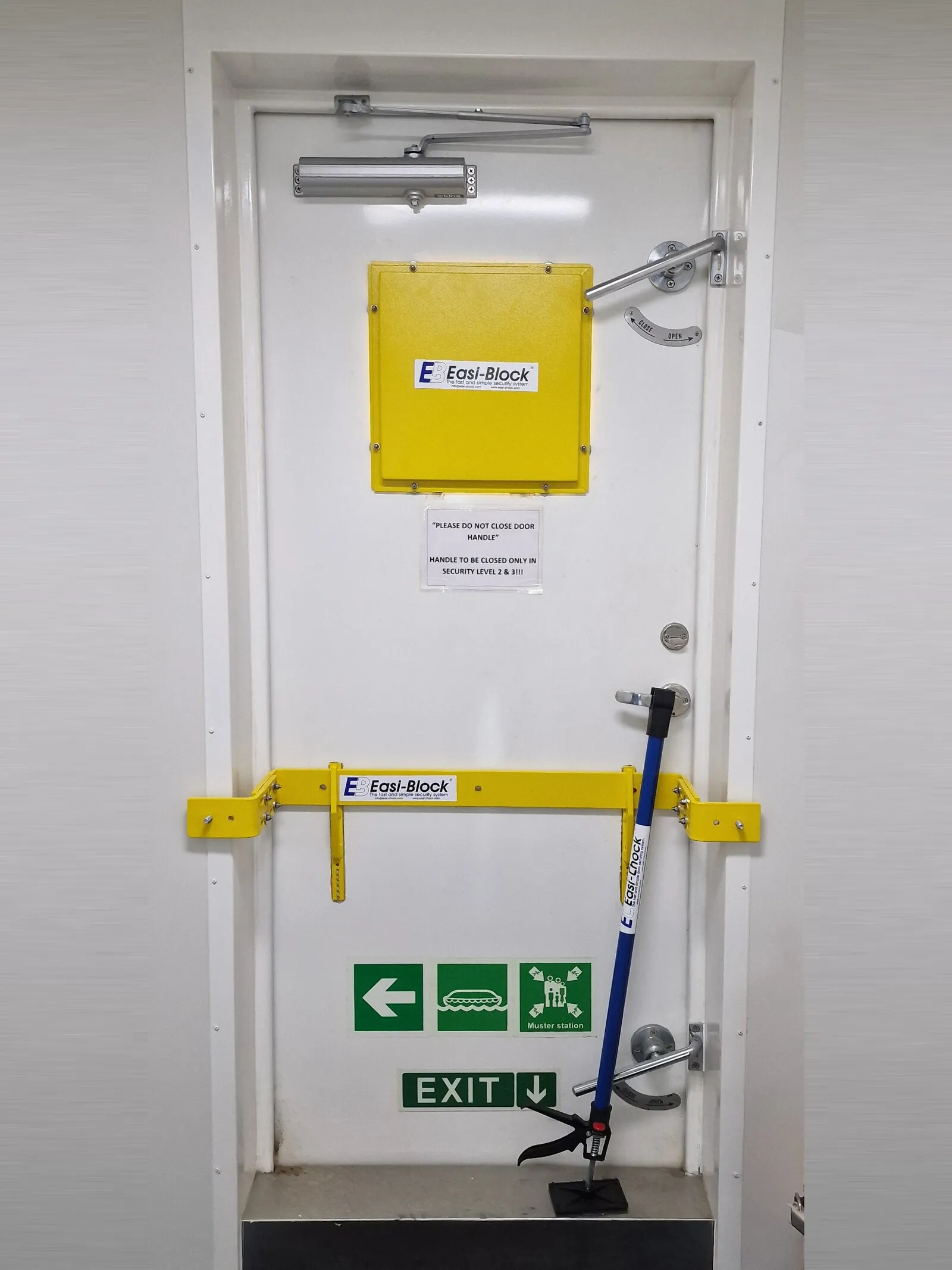 A secured weathertight door: an Easi-Block single drop-down bar across the door, an Easi-Block porthole protection plate above it, and an Easi-Chock Type 1 braced under the handle